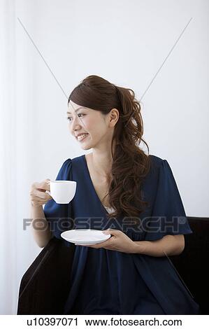 Young woman holding a cup of coffee View Large Photo Image Stock Image - Young woman holding a cup of coffee. Fotosearch