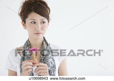 Young woman holding a flower View Large Photo Image Stock Image - Young woman holding a flower. Fotosearch