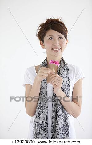 Young woman holding a flower View Large Photo Image Stock Image - Young woman holding a flower. Fotosearch
