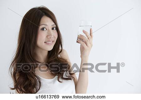 Young woman holding a glass of water View Large Photo Image Stock Photo - Young woman holding a glass of water. Fotosearch