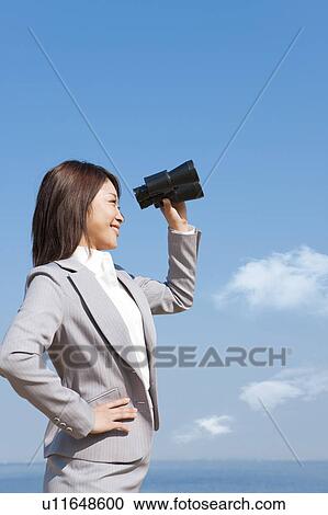 Stock Image - Young woman holding binoculars. Fotosearch