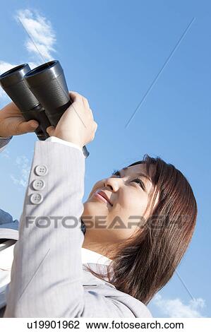 Stock Image - Young woman holding binoculars. Fotosearch