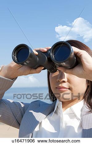 Young woman holding binoculars View Large Photo Image Stock Photograph - Young woman holding binoculars. Fotosearch