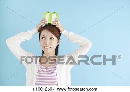 Young Woman Holding Gift On Top Of Her Head View Large Photo Image Stock Photo - Young Woman Holding Gift On Top Of Her Head. Fotosearch