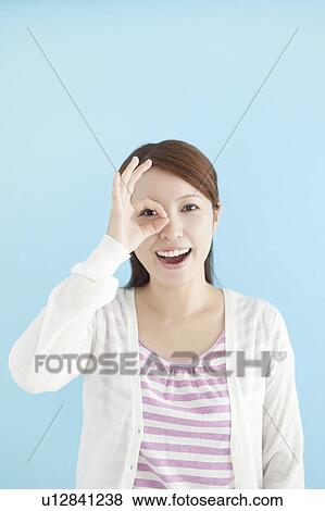 Stock Photo - Young Woman Looking Through Fingers. Fotosearch