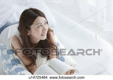 Young woman reading a book on bed View Large Photo Image Picture - Young woman reading a book on bed. Fotosearch