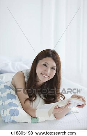 Young woman reading a book on bed View Large Photo Image Stock Photo - Young woman reading a book on bed. Fotosearch