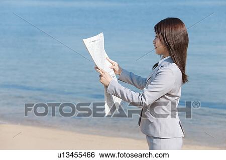 Young woman reading a newspaper View Large Photo Image Stock Photograph - Young woman reading a newspaper. Fotosearch