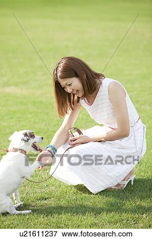 Stock Photo - Young woman shaking hands with a dog. Fotosearch