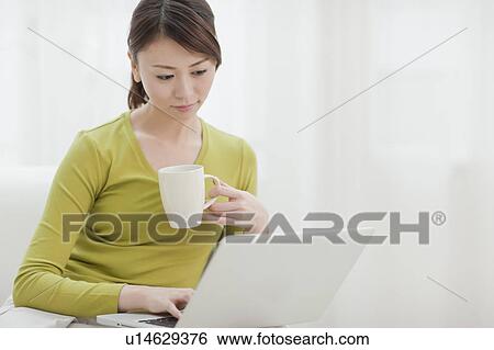 Young Woman Using Laptop and Having Drink View Large Photo Image Stock Photograph - Young Woman Using Laptop and Having Drink. Fotosearch