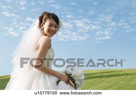 Stock Image - Young woman wearing a wedding dress. Fotosearch