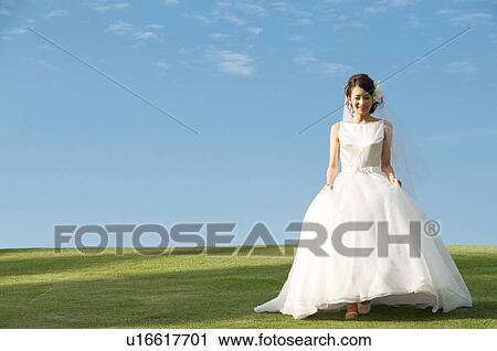 Stock Image - Young woman wearing a wedding dress. Fotosearch