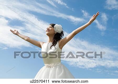 Young woman wearing a wedding dress with arms raised View Large Photo Image Stock Image - Young woman wearing a wedding dress with arms raised. Fotosearch