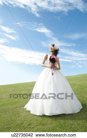 Stock Image - Young woman wearing a wedding dress. Fotosearch