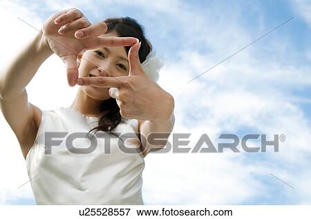 Stock Photo - Young woman wearing a wedding dress making frame with hands. Fotosearch