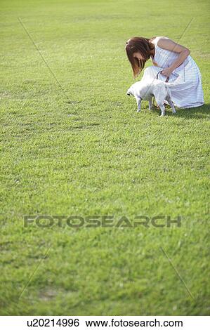 Stock Photograph - Young woman with a dog outdoors. Fotosearch
