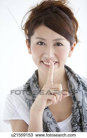 Young woman with finger on lips View Large Photo Image Stock Image - Young woman with finger on lips. Fotosearch