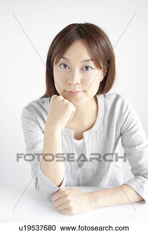 Stock Image - Young woman with hand on chin. Fotosearch