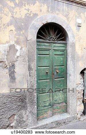 Stock Image - Detail of delapidated house wih fading paintwork on stone and stucco, old green wooden door, Northern Italy. Fotosearch