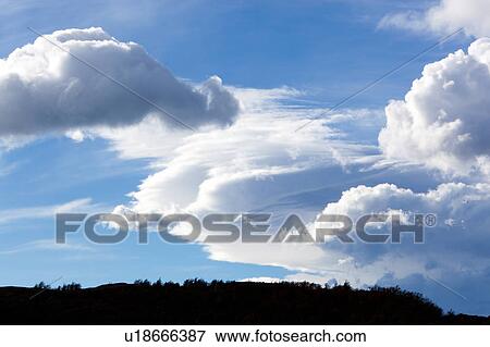 Stock Photo - Dramatic lenticular clouds against blue sky, and hills silhouetted in foreground, Torres del Paine, Southern Chile, Patagonia. Fotosearch