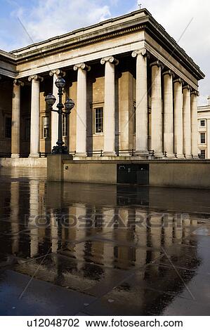 Exterior view of British Museum beside entrance with columned facade reflected in wet pavement in sunshine with blue sky, after rain, London, England View Large Photo Image Stock Image - Exterior view of British Museum beside entrance with columned facade reflected in wet pavement in sunshine with blue sky, after rain, London, England. Fotosearch