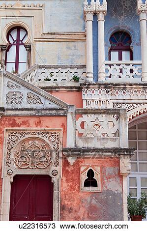 Stock Image - Frontal detail: facade of colourful Moorish style 19th century Villa Sticchi, with stucco painted blue, orange and pink, Santa Cesarea Terme, Salento, Puglia, Southern Italy. Fotosearch