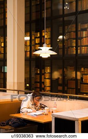 Interior of British Library, London, England, showing foreground single figure seated at table, reading lamp overhead, with glass shelves of books floor to ceiling behind View Large Photo Image Stock Image - Interior of British Library, London, England, showing foreground single figure seated at table, reading lamp overhead, with glass shelves of books floor to ceiling behind. Fotosearch