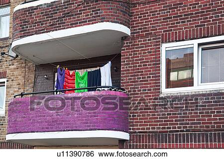 Stock Photograph - Modern red brick tenement building, with brick balcony painted purple, and gaily coloured laundry hanging on line, Dublin, Southern ireland. Fotosearch
