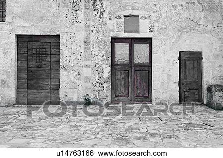 Monochrome view of ancient wooden doors set into stone walls of tufa houses (Sassi), paved courtyard, Matera, Puglia, Southern Italy View Large Photo Image Stock Photograph - Monochrome view of ancient wooden doors set into stone walls of tufa houses (Sassi), paved courtyard, Matera, Puglia, Southern Italy. Fotosearch