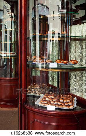 Old fashioned polished mahogany and curved glass pastry shop window, piled with cupcakes and desserts, with reflection, sunny morning, Salento, Puglia, Southern Italy View Large Photo Image Stock Photo - Old fashioned polished mahogany and curved glass pastry shop window, piled with cupcakes and desserts, with reflection, sunny morning, Salento, Puglia, Southern Italy. Fotosearch