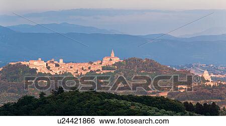Stock Photograph - Panorama view of medieval hilltop town of Todi, at sunset, with spire of San Fortunato, and Tempio of Bramante, Umbria, Italy. Fotosearch