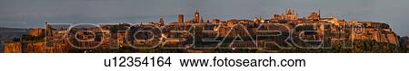 Picture - Panorama view of Orvieto city skyline at dusk, with duomo facade lit by setting sun, Italy. Fotosearch