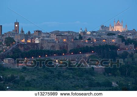 Panorama view of Orvieto city skyline at dusk, with duomo facade lit by setting sun, Italy View Large Photo Image Stock Photo - Panorama view of Orvieto city skyline at dusk, with duomo facade lit by setting sun, Italy. Fotosearch