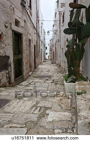 Street in Ostuni, with typical white stucco walls, stone paving, wrought iron lamp, and archway, with flowers decorating, spring afternoon, Salento, Puglia, Southern Italy View Large Photo Image Stock Image - Street in Ostuni, with typical white stucco walls, stone paving, wrought iron lamp, and archway, with flowers decorating, spring afternoon, Salento, Puglia, Southern Italy. Fotosearch