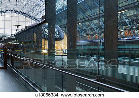 Picture - Upper concourse of St. Pancras International railway station, London, England, showing glass and metal domed ceiling, platform, with stationary train, front/side view in foreground. Fotosearch