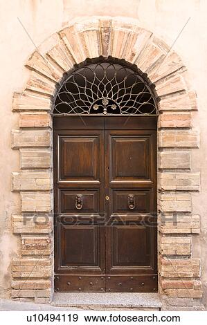 Stock Photo - View of old double wooden arched door of stone medieval palace, with decorative wrought iron grille above door, Montefalco, Umbria, Italy. Fotosearch