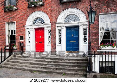 Stock Photo - View of traditional Georgian red brick row houses with stairway to ornate arched red and blue doorways, wrought iron railing and lamp, Dublin, Southern Ireland. Fotosearch
