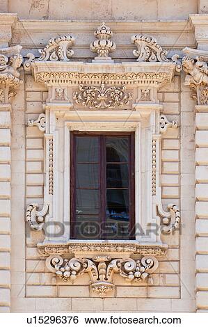 Stock Photograph - Window detail: ornate Baroque facade of Palazzo del Seminario, ornately carved in Leccese style, 8 - paned window, reflection of Duomo and balustrade, Lecce, Salento, Puglia, Southern Italy. Fotosearch