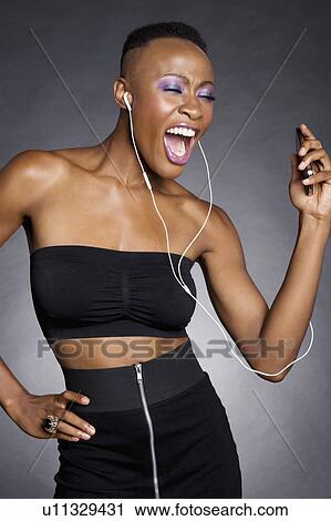 Stock Image - African American woman listening to headphones. Fotosearch