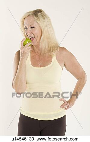Beautiful mature woman eating a fresh green apple View Large Photo Image Stock Image - Beautiful mature woman eating a fresh green apple. Fotosearch
