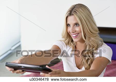 Beautiful woman using Tablet PC as remote control View Large Photo Image Stock Photo - Beautiful woman using Tablet PC as remote control. Fotosearch