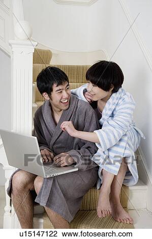 Cheerful young couple sitting on stairway using laptop View Large Photo Image Stock Image - Cheerful young couple sitting on stairway using laptop. Fotosearch