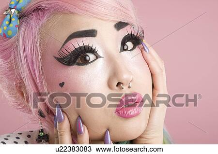 Stock Image - Close-up of scared young woman over pink background. Fotosearch