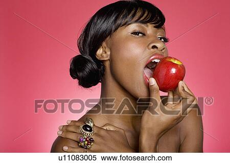 Stock Photography - Close up of woman taking a bite of apple. Fotosearch