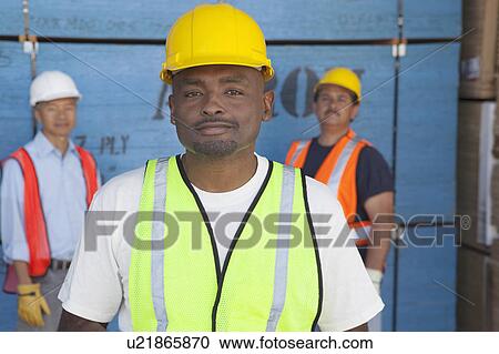 Close-up portrait of a smiling mid-adult man with colleagues in background View Large Photo Image Stock Image - Close-up portrait of a smiling mid-adult man with colleagues in background. Fotosearch