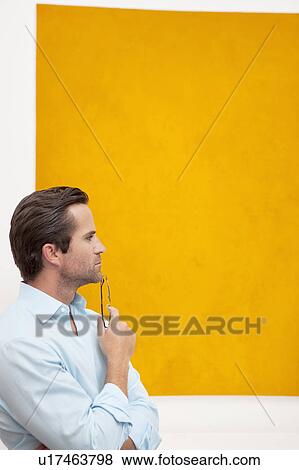 Stock Photo - Close-up view of a thoughtful young man in front of wall painting. Fotosearch