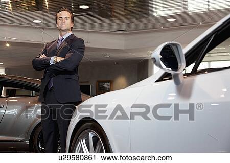 Confident car salesperson standing with arms crossed View Large Photo Image Stock Image - Confident car salesperson standing with arms crossed. Fotosearch