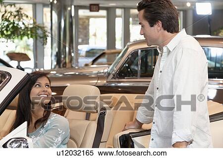 Couple checking out new cars in dealership showroom View Large Photo Image Stock Photography - Couple checking out new cars in dealership showroom. Fotosearch
