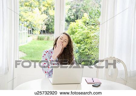 Stock Image - Exhaust young woman sitting in front of laptop. Fotosearch