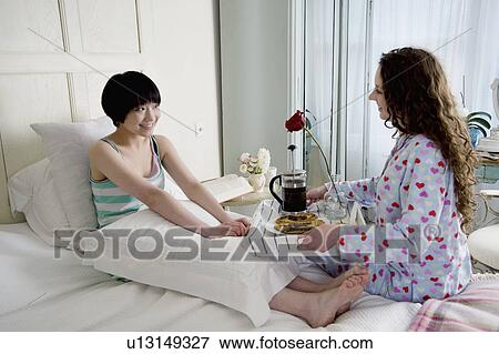 Stock Photo - Female friend bringing breakfast for her friend. Fotosearch